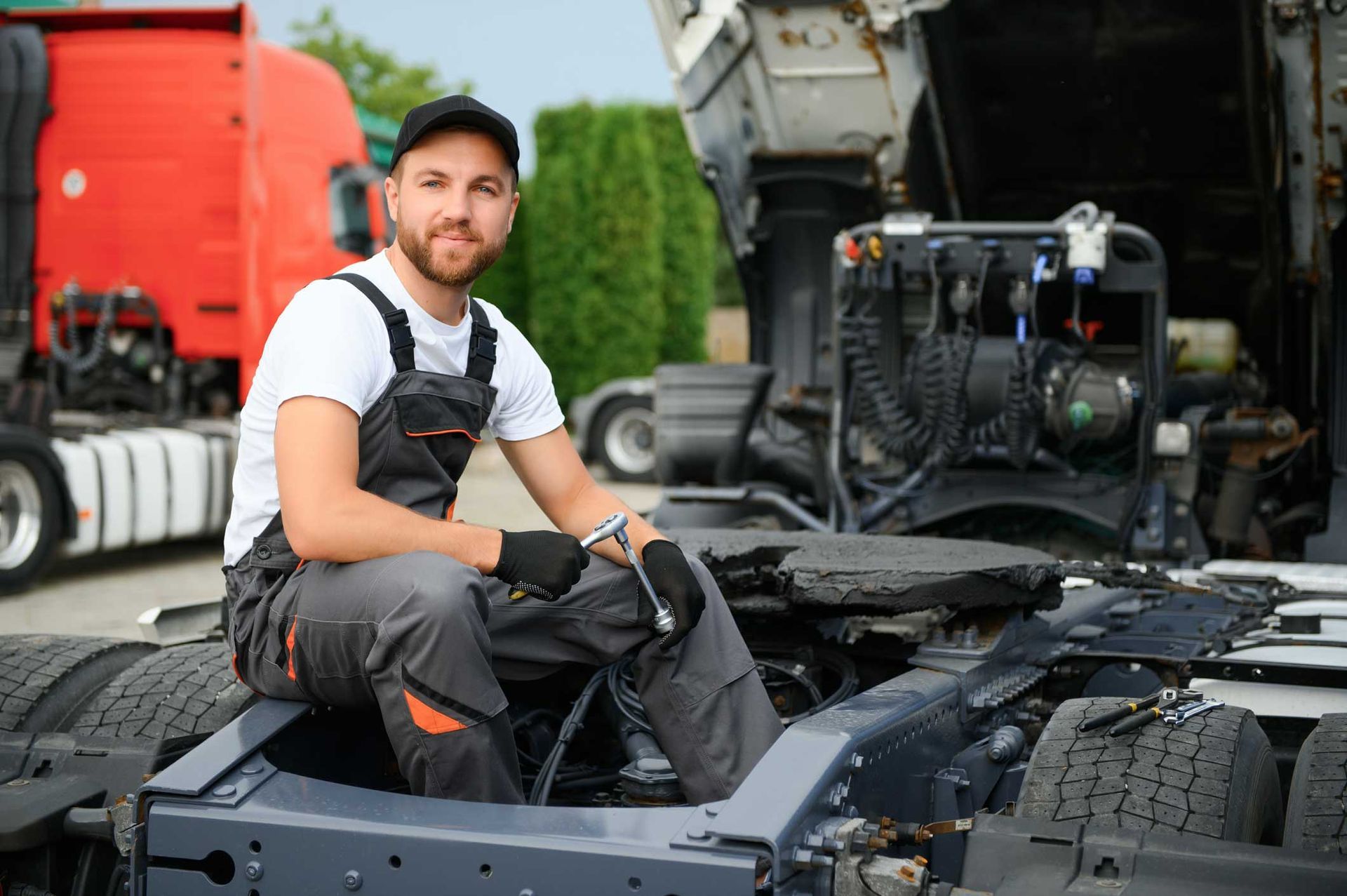 A semi-truck under maintenance. A truck mechanic is working to fix it.