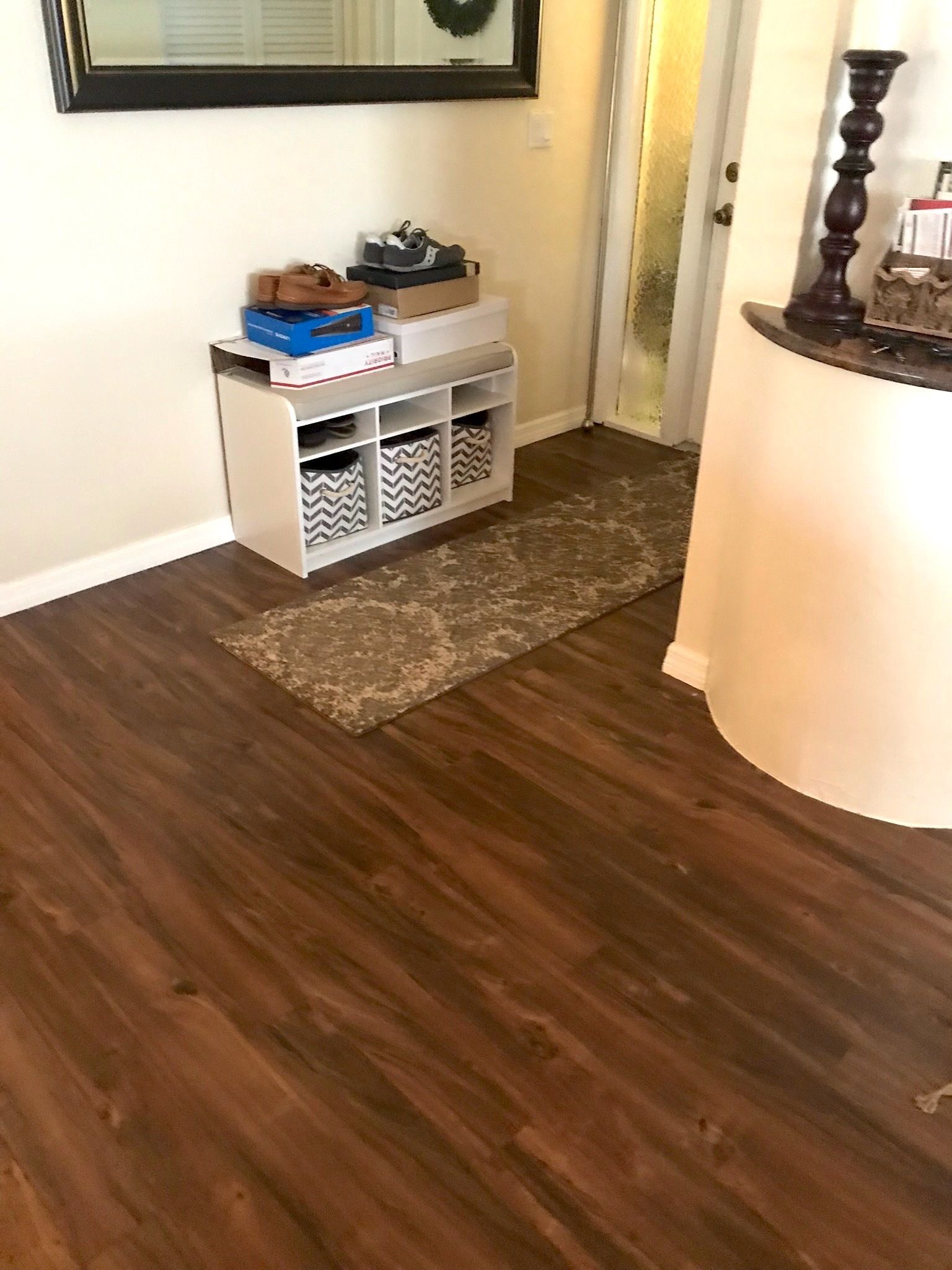 A room with a wooden floor and a shelf with baskets on it.