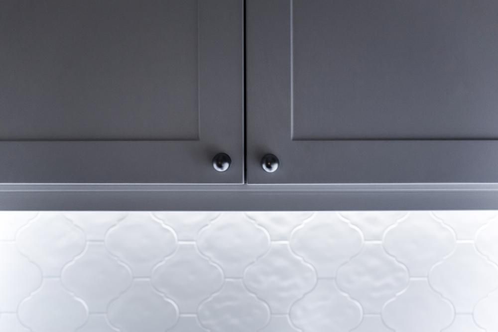 A Close Up Of A Gray Cabinet With Black Handles On A White Tile Floor — North Coast Cabinetmaking Pty Ltd In Whitsundays, QLD