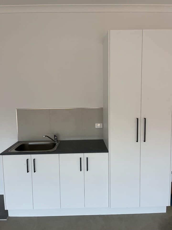 An Empty Kitchen With White Cabinets And A Sink — North Coast Cabinetmaking Pty Ltd In Proserpine, QLD