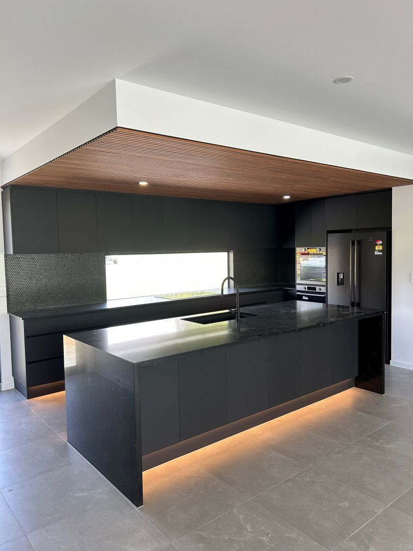 A Large Empty Room With A Kitchen With Black Cupboards — North Coast Cabinetmaking Pty Ltd In Proserpine, QLD