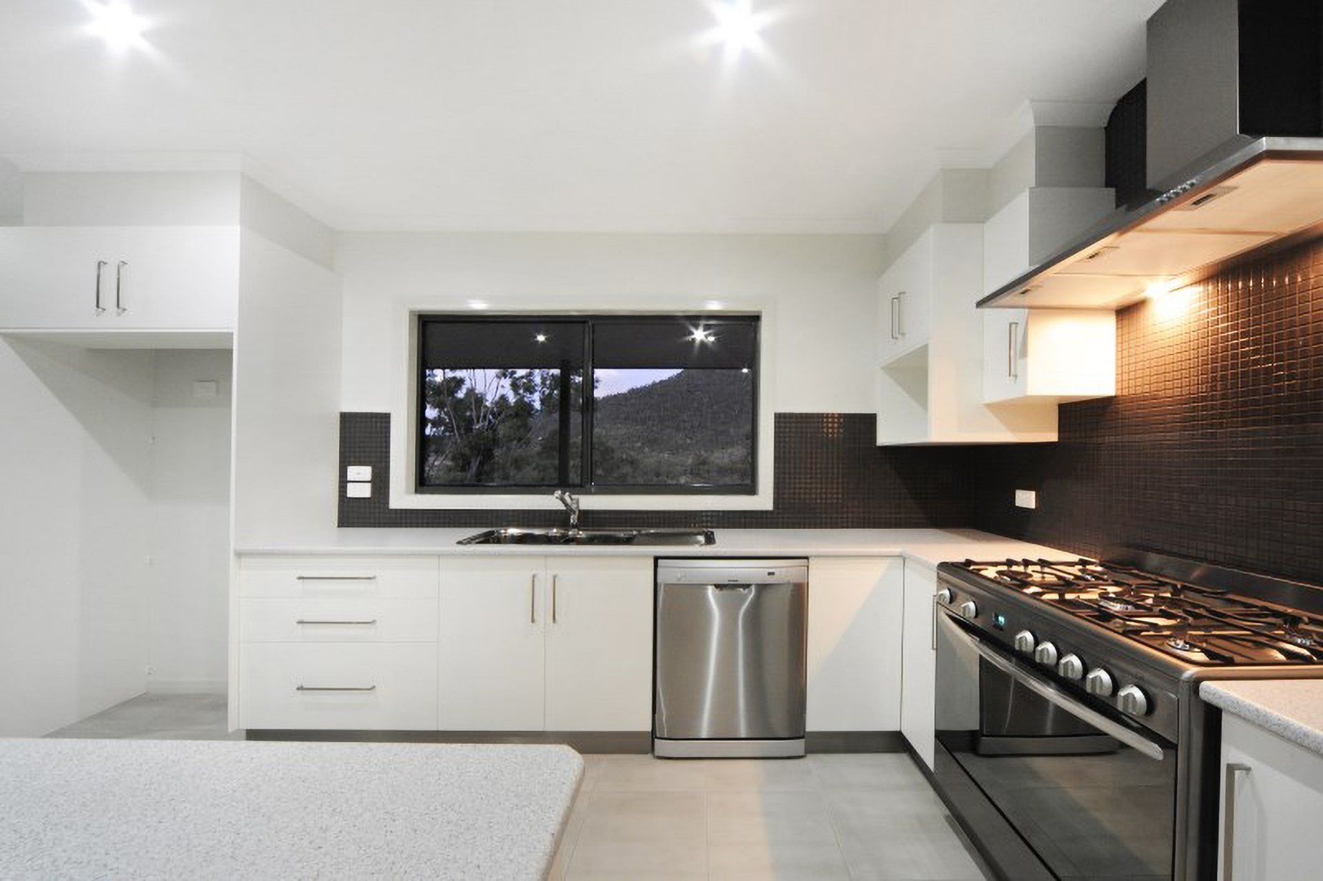 A Kitchen With White Cabinets And Stainless Steel Appliances — North Coast Cabinetmaking Pty Ltd In Proserpine, QLD