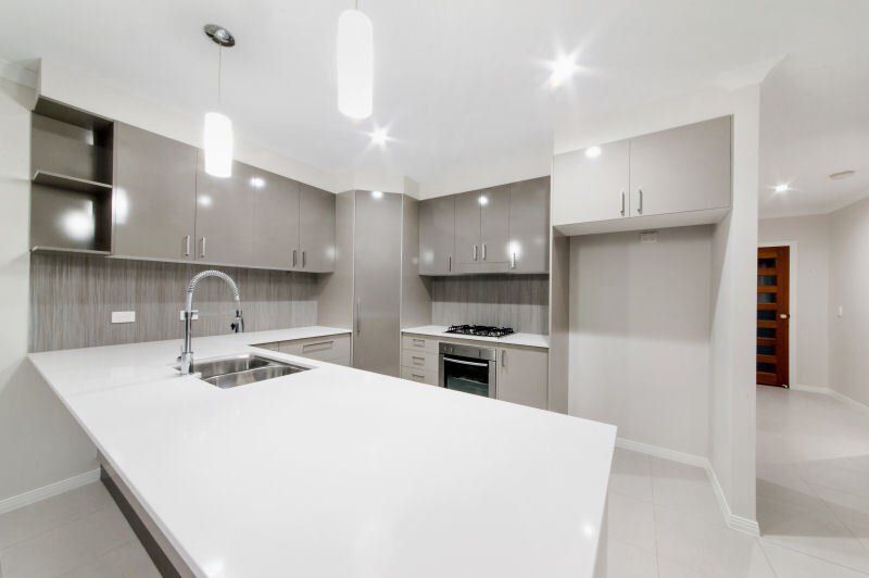 An Empty Kitchen With White Counter Tops And Gray Cabinets — North Coast Cabinetmaking Pty Ltd In Proserpine, QLD