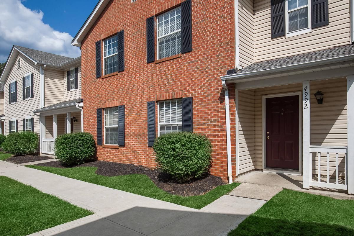 Row of townhomes with brick and beige exteriors, black shutters, and front doors.