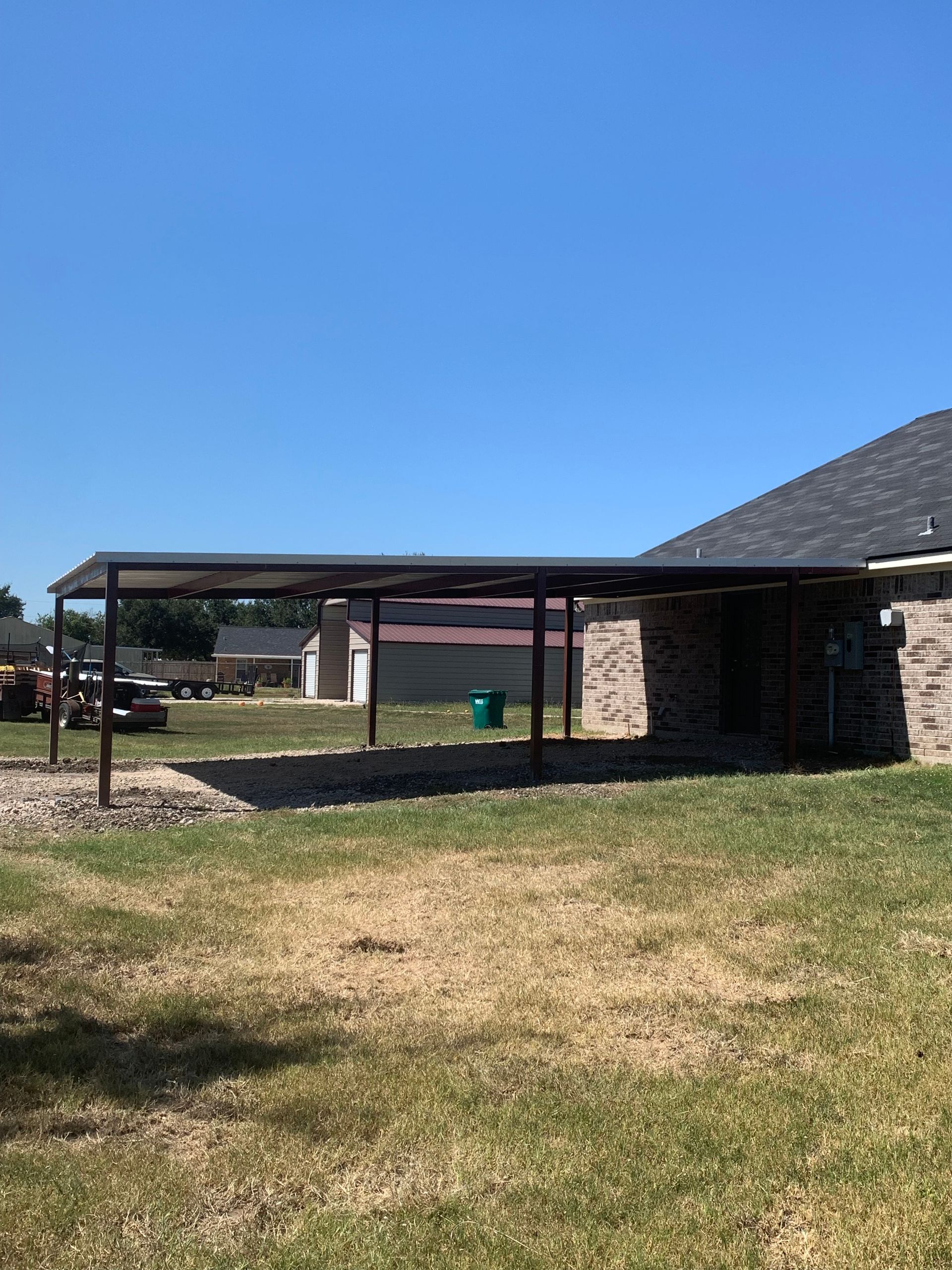 There is a carport in the backyard of a house.