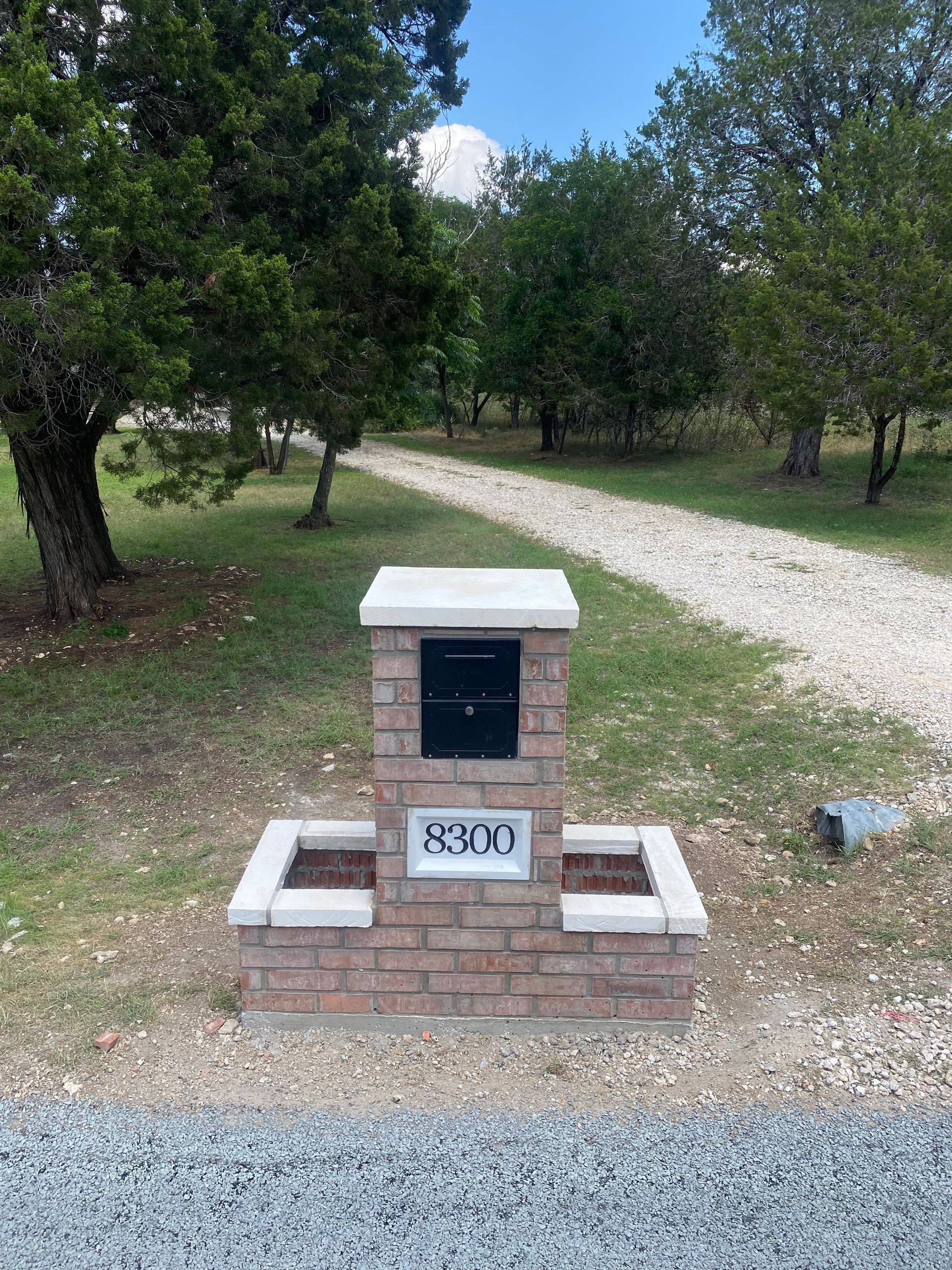 A brick mailbox is sitting on the side of a dirt road.