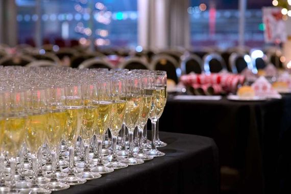 Rows of champagne flutes filled with drinks on a banquet table at an event