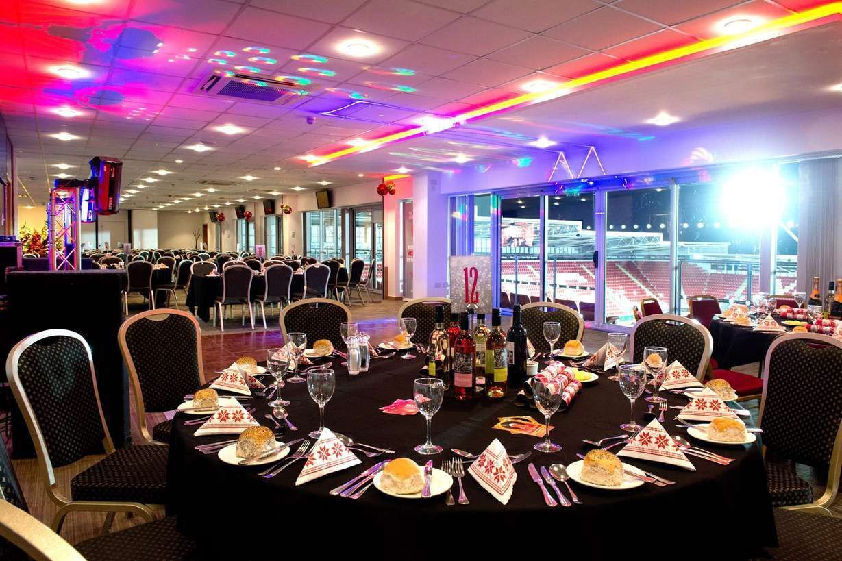 Elegant banquet hall with set round tables, black chairs, and colorful ceiling lights at night
