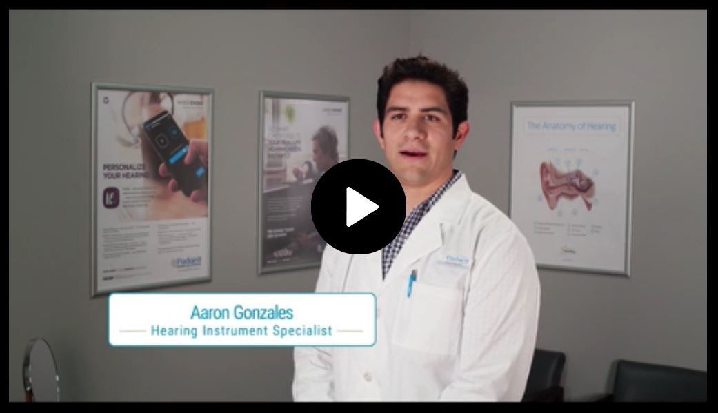 A man in a white coat is standing in front of a play button