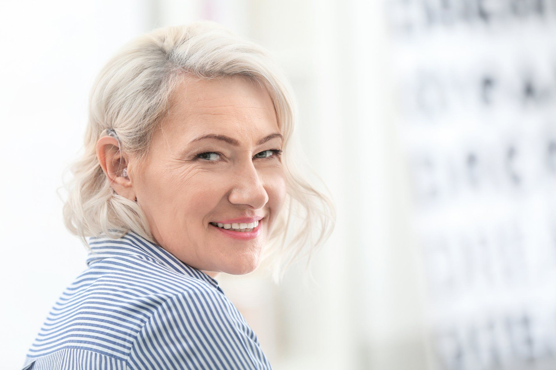 A woman with gray hair is smiling and looking at the camera.