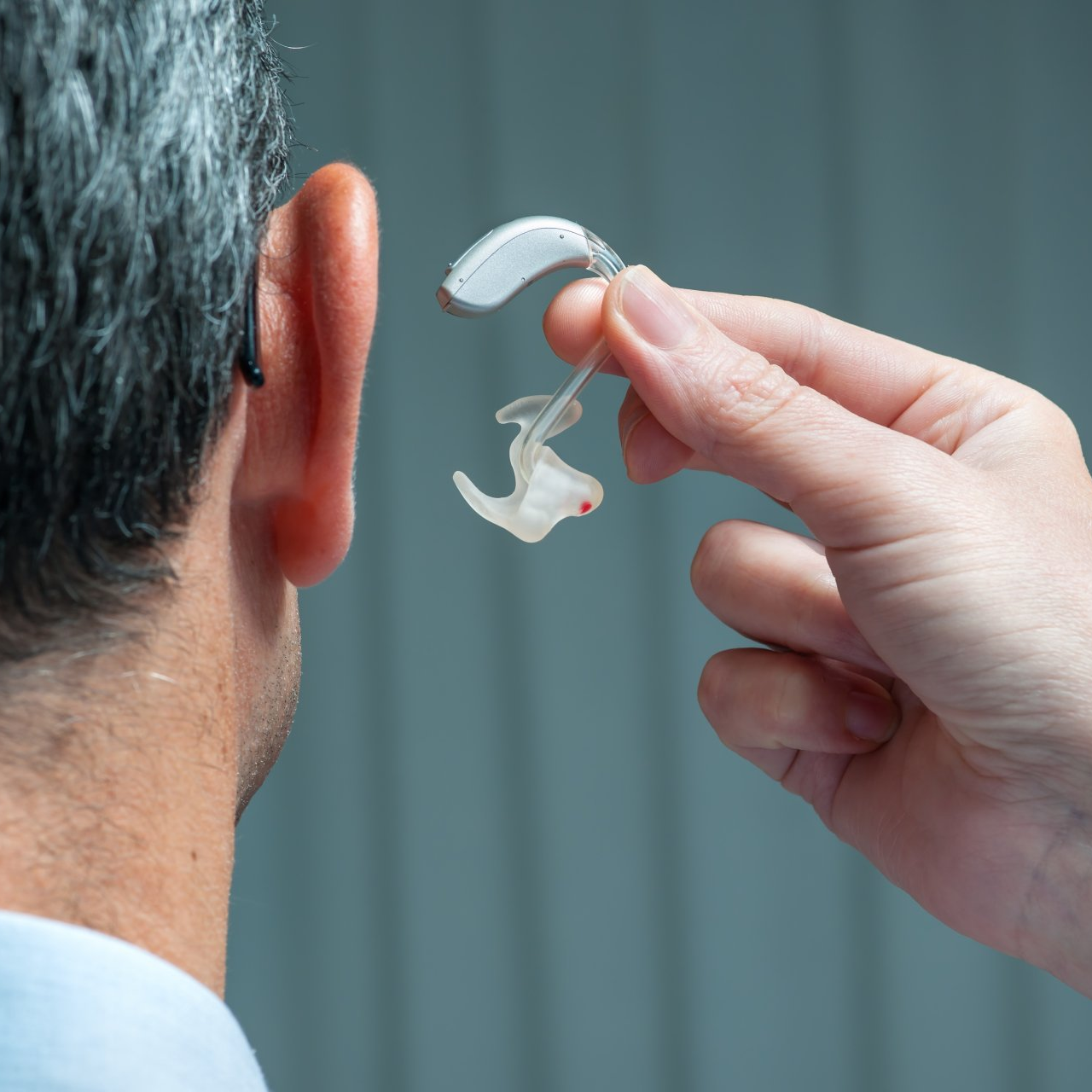 putting hearing aid to a man
