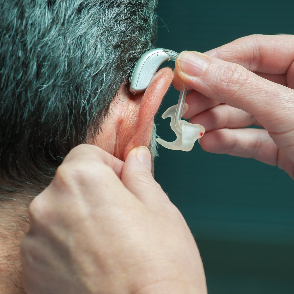 putting hearing aid to a man