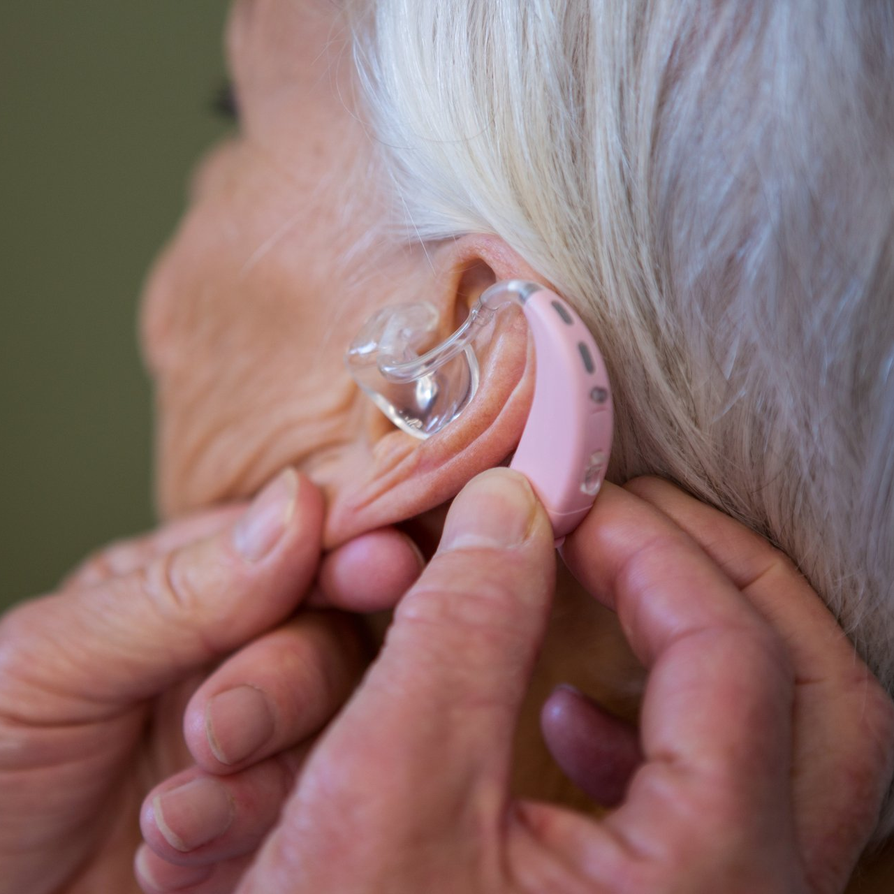 putting hearing aid to an old woman