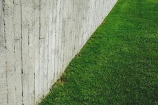 A concrete fence surrounds a lush green lawn.