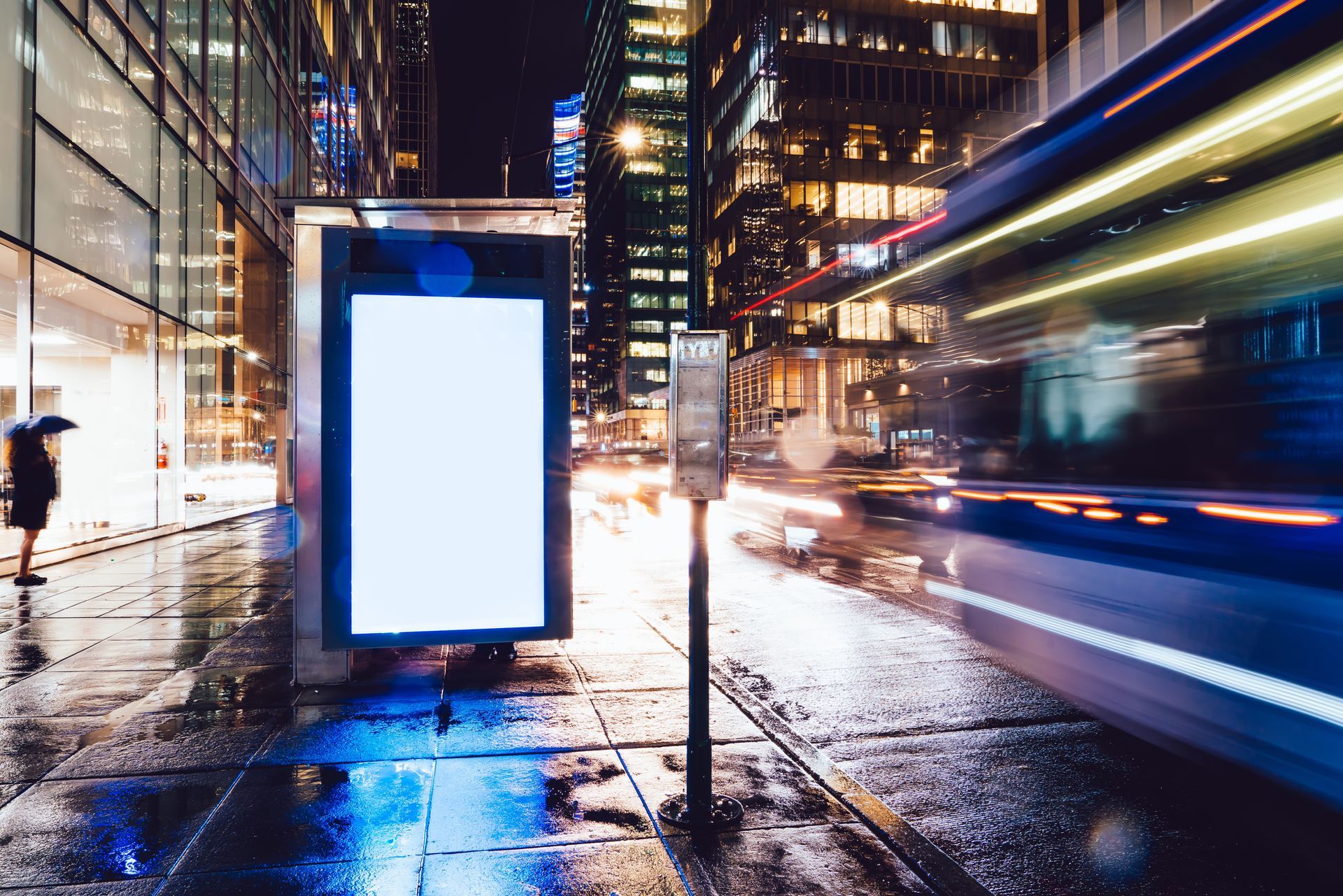 A woman is sitting at a table with a tablet in front of a television.