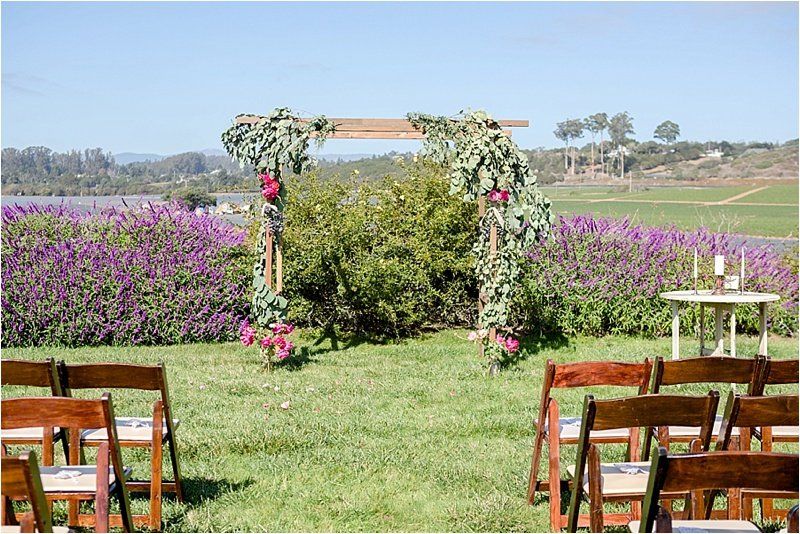 A wedding ceremony is taking place in a field with purple flowers.