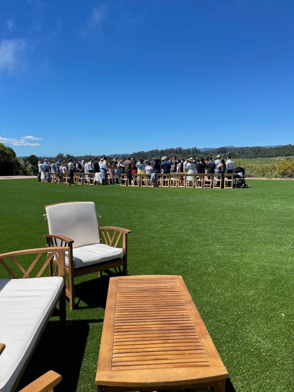 A group of people are sitting at tables in a grassy field.