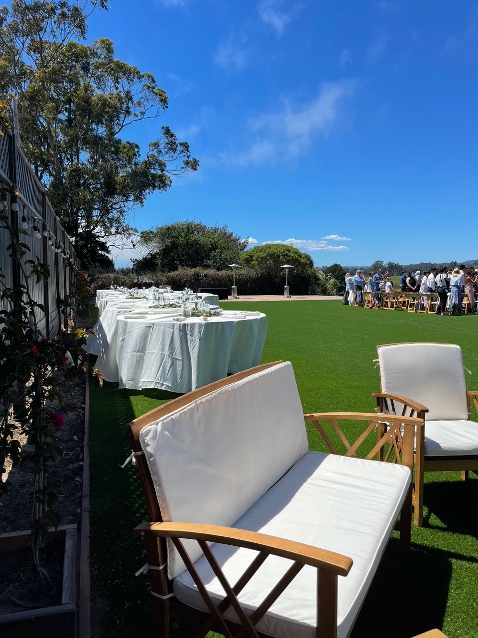 A lawn with a couch and chairs and tables in the background