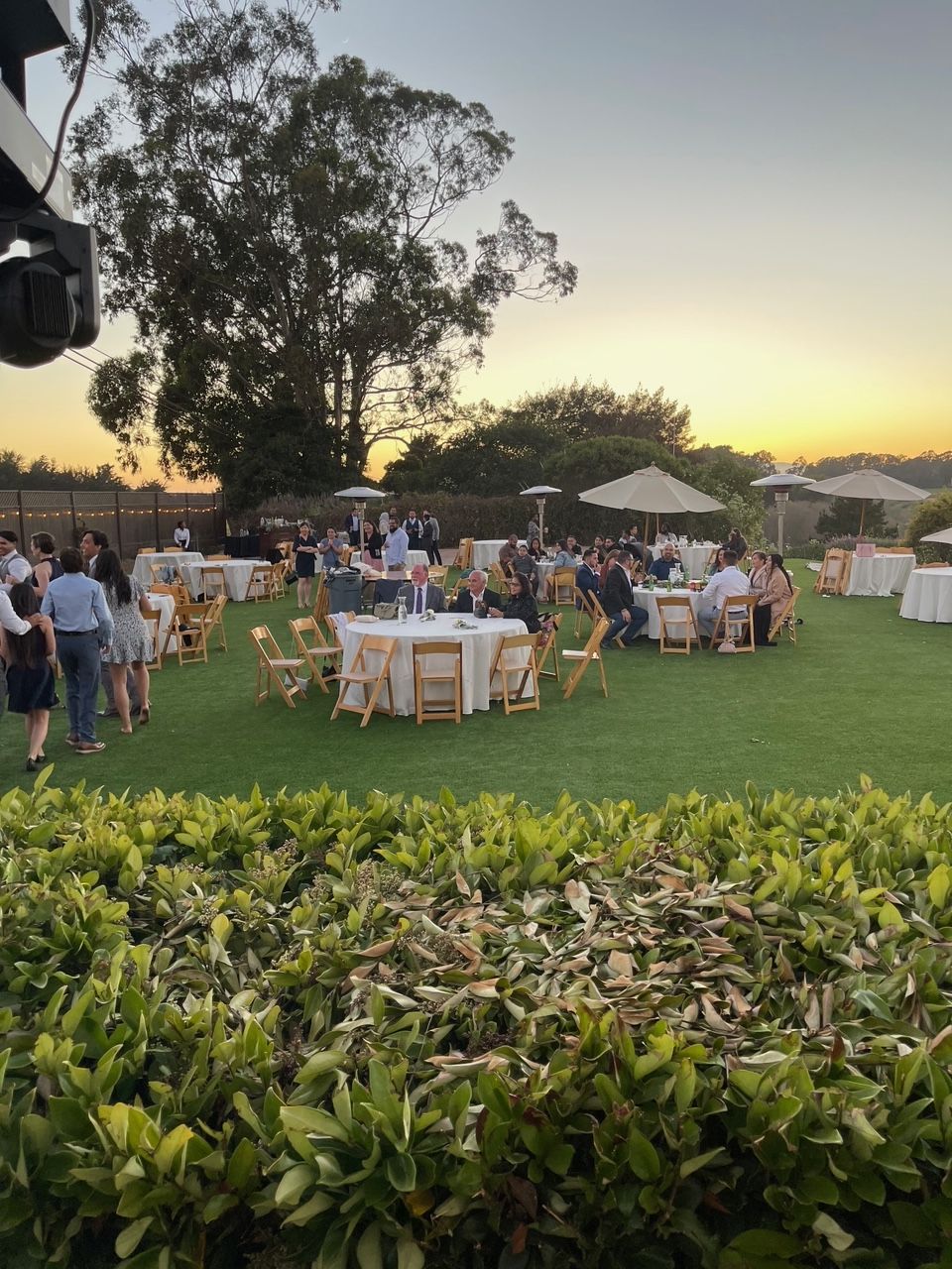 A group of people are sitting at tables in a grassy field.