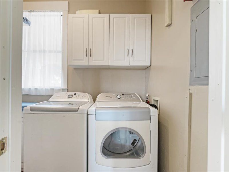 A laundry room with a washer and dryer and white cabinets.
