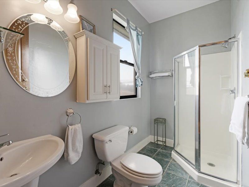 A bathroom with a toilet , sink and shower.