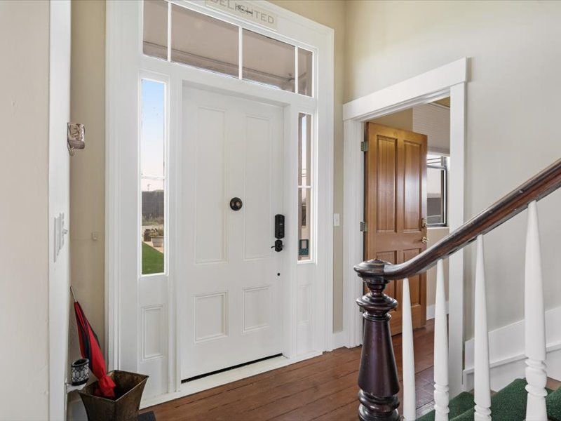 A hallway with a white door and stairs leading up to it.