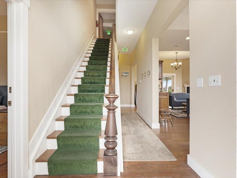 A staircase with green carpet leading up to the second floor of a house