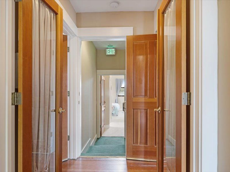 A hallway with a green exit sign above the door