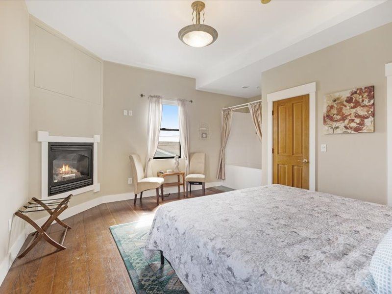 A bedroom with a bed , chairs and a fireplace.