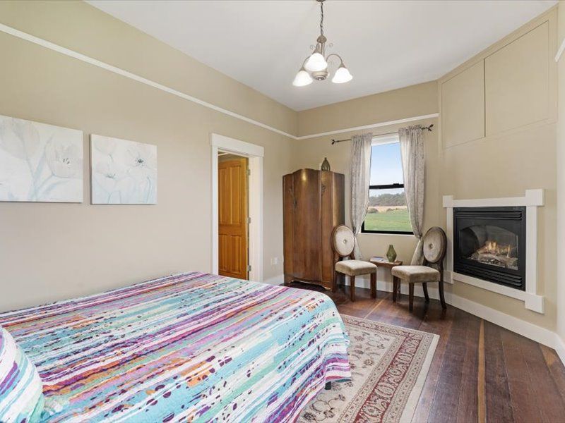 A bedroom with a bed , chairs and a fireplace.