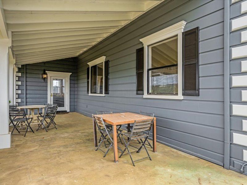 There is a table and chairs on the porch of a house.