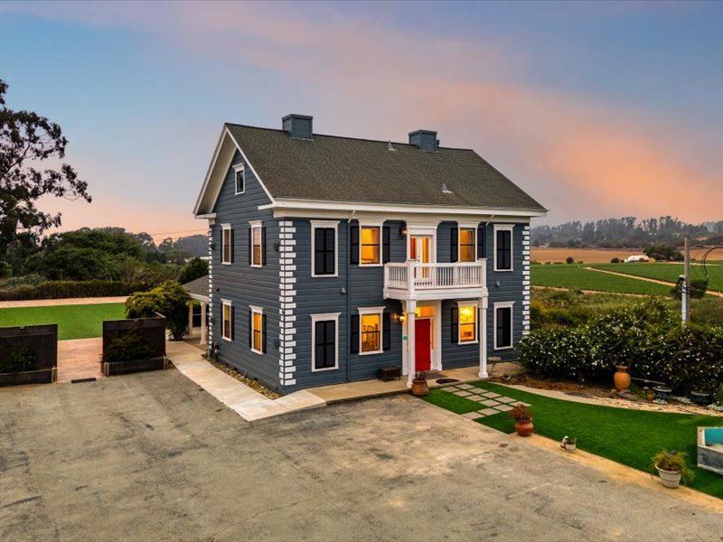 An aerial view of a large blue house with a red door