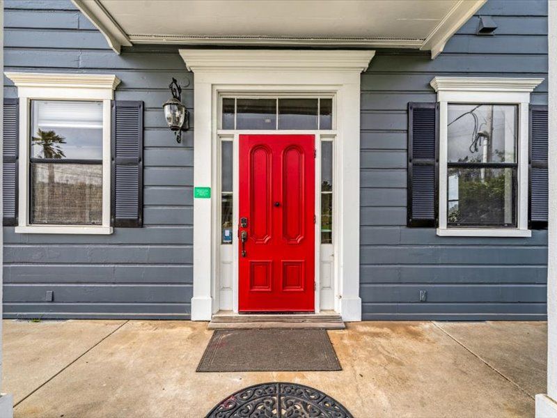 The front door of a house with a red door and black shutters