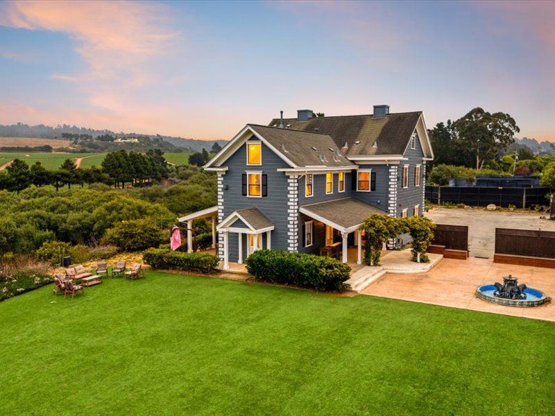 An aerial view of a large house with a large lawn in front of it.