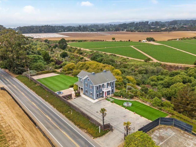 An aerial view of a house sitting on the side of a road next to a field.