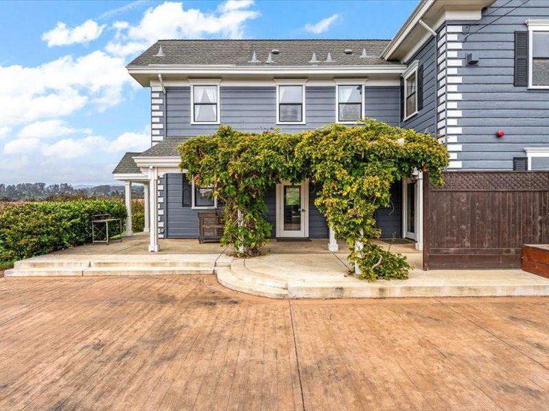 A large gray house with a concrete driveway and a covered porch.