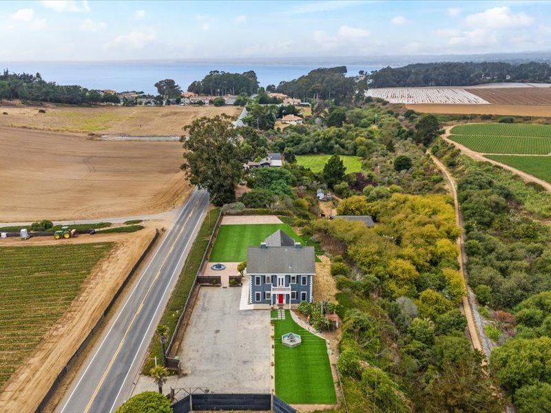 An aerial view of a house surrounded by fields and trees