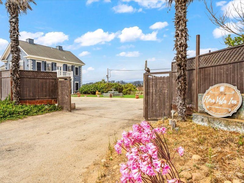 A large house is behind a wooden fence with a sign that says ' mrs. villa inn ' on it.
