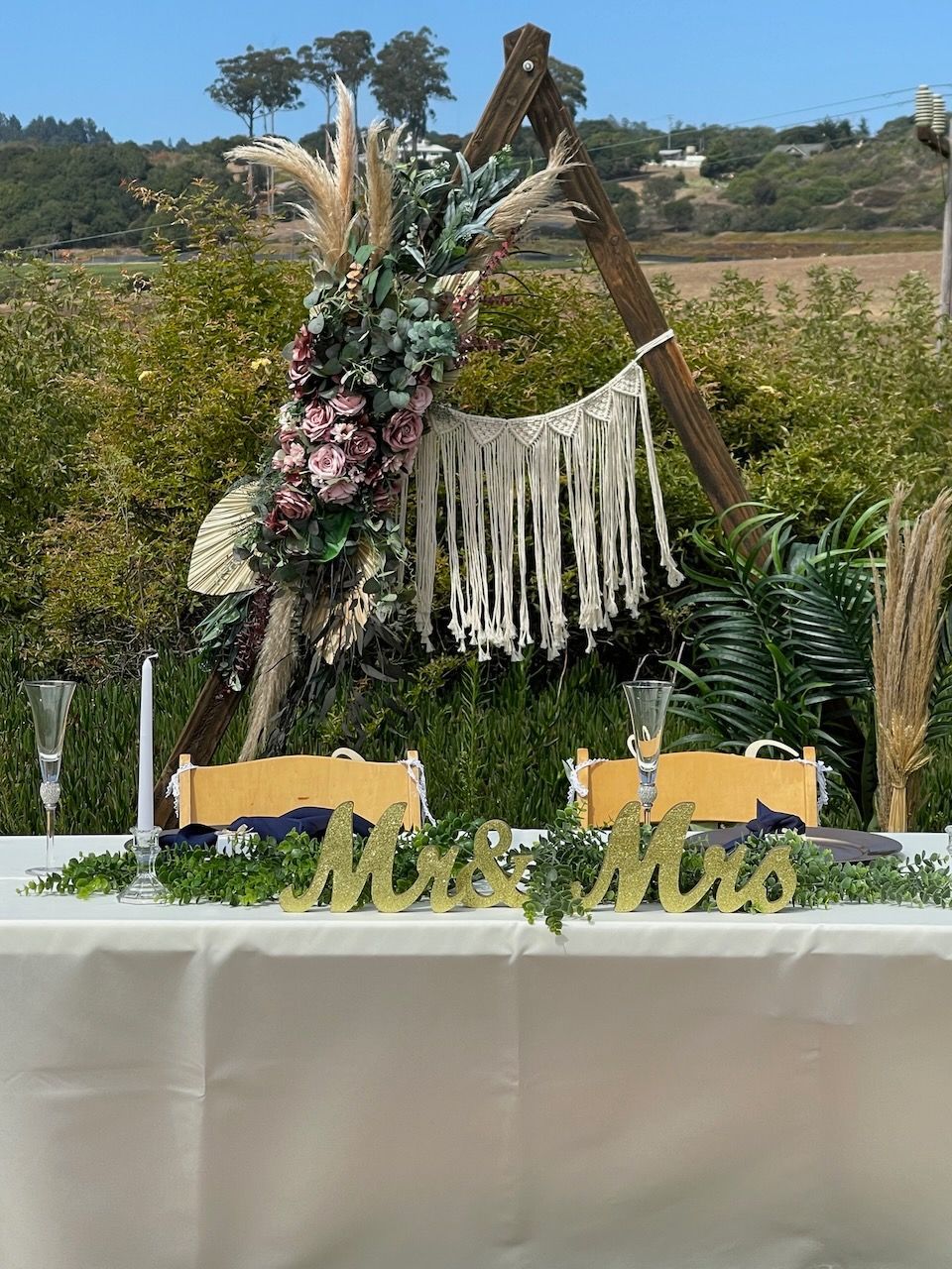 A wedding table with a wooden arch and flowers on it.