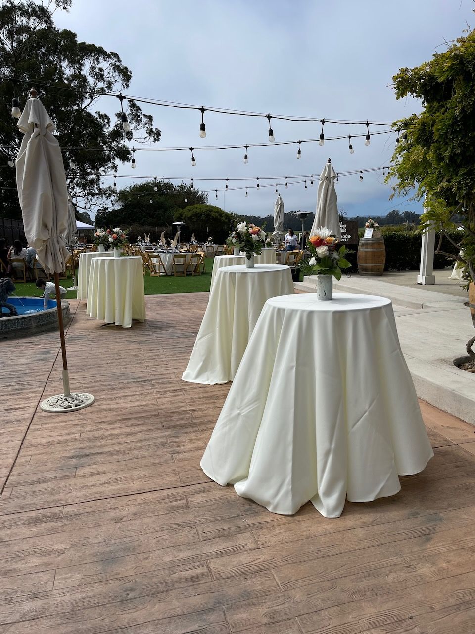 A patio with tables and umbrellas set up for a party