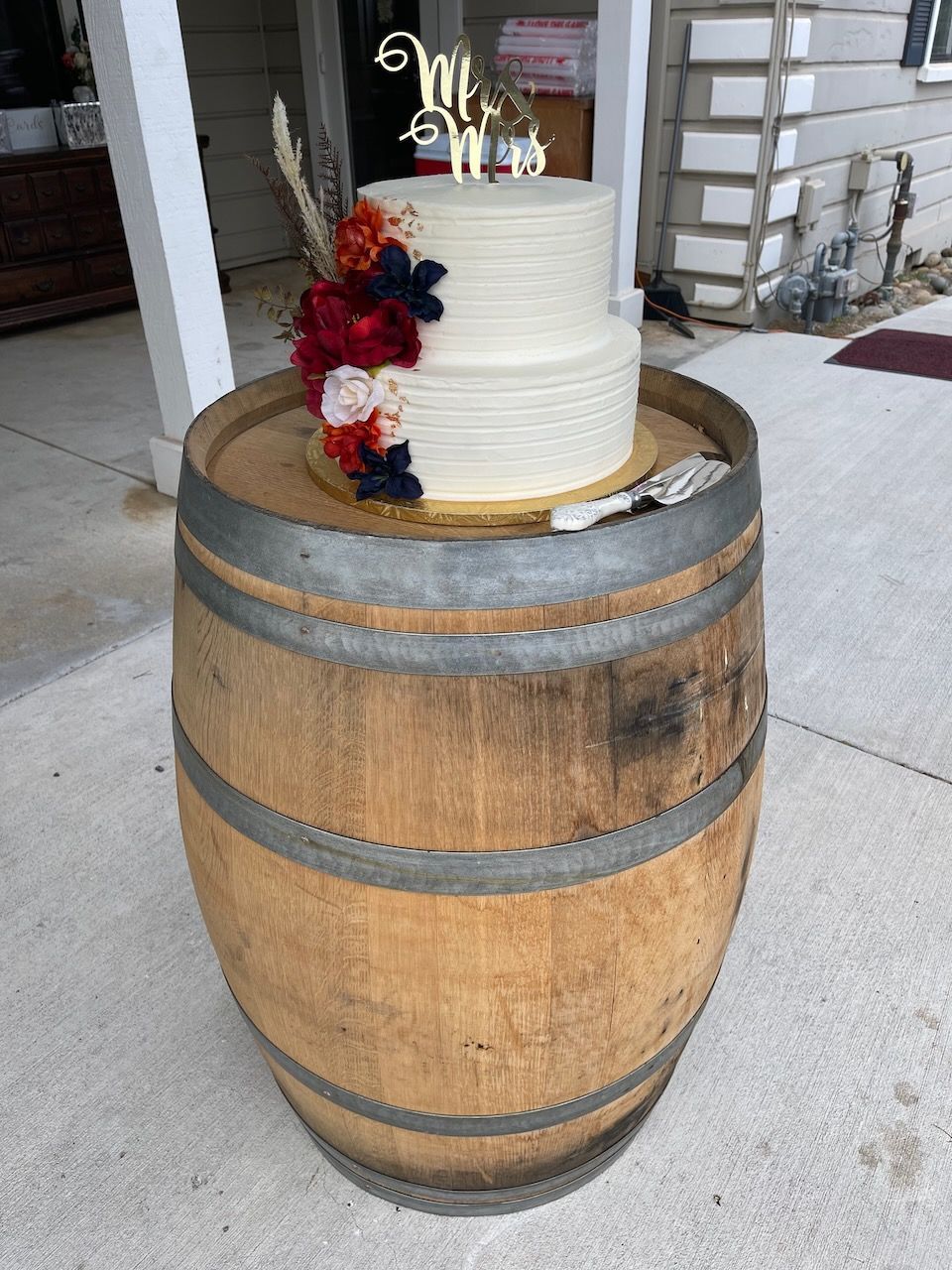 A wedding cake is sitting on top of a wooden barrel.
