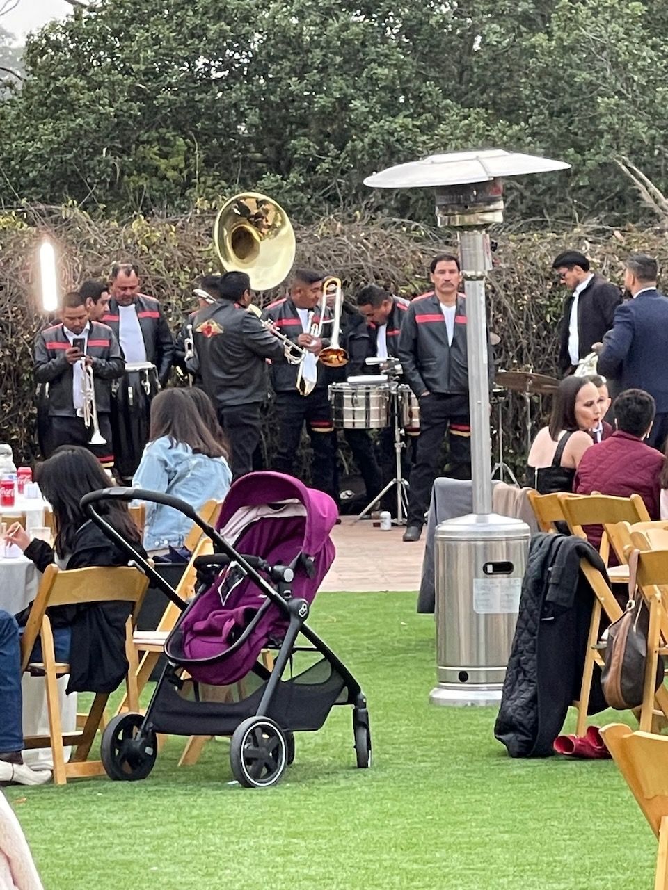 A baby stroller is sitting in front of a band playing instruments.