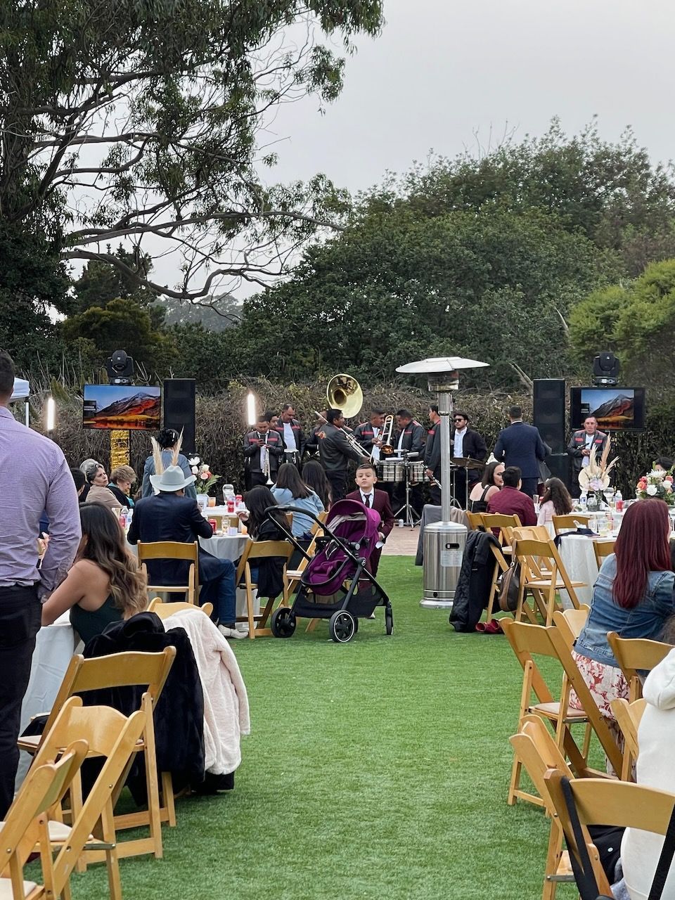 A group of people are sitting at tables and chairs in a park.