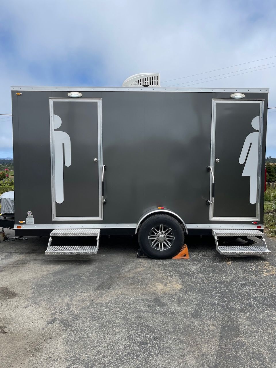 A trailer with two toilets on it is parked in a parking lot.