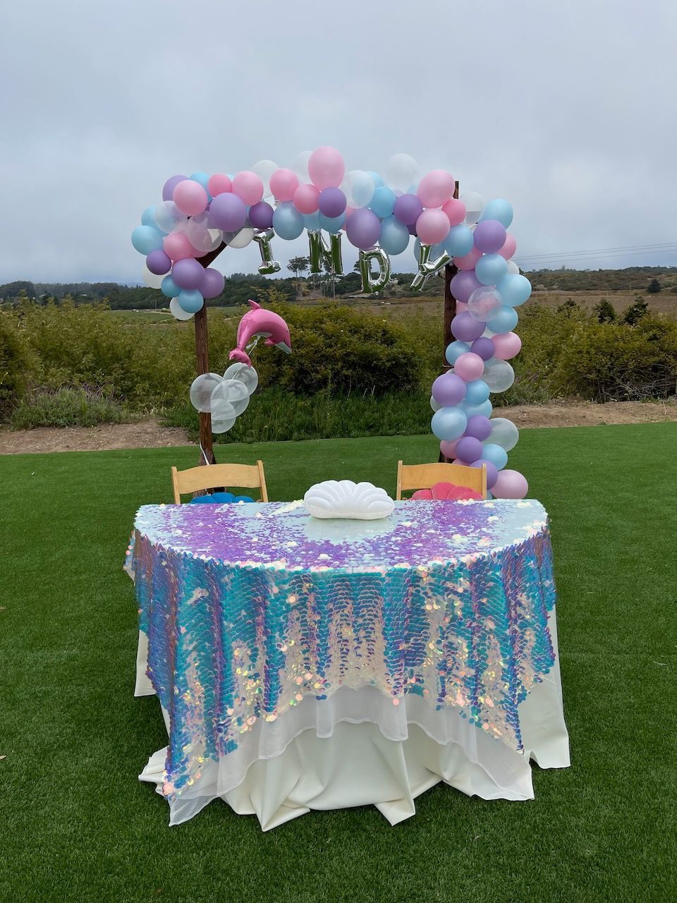 A table with a sequined tablecloth and balloons on it.
