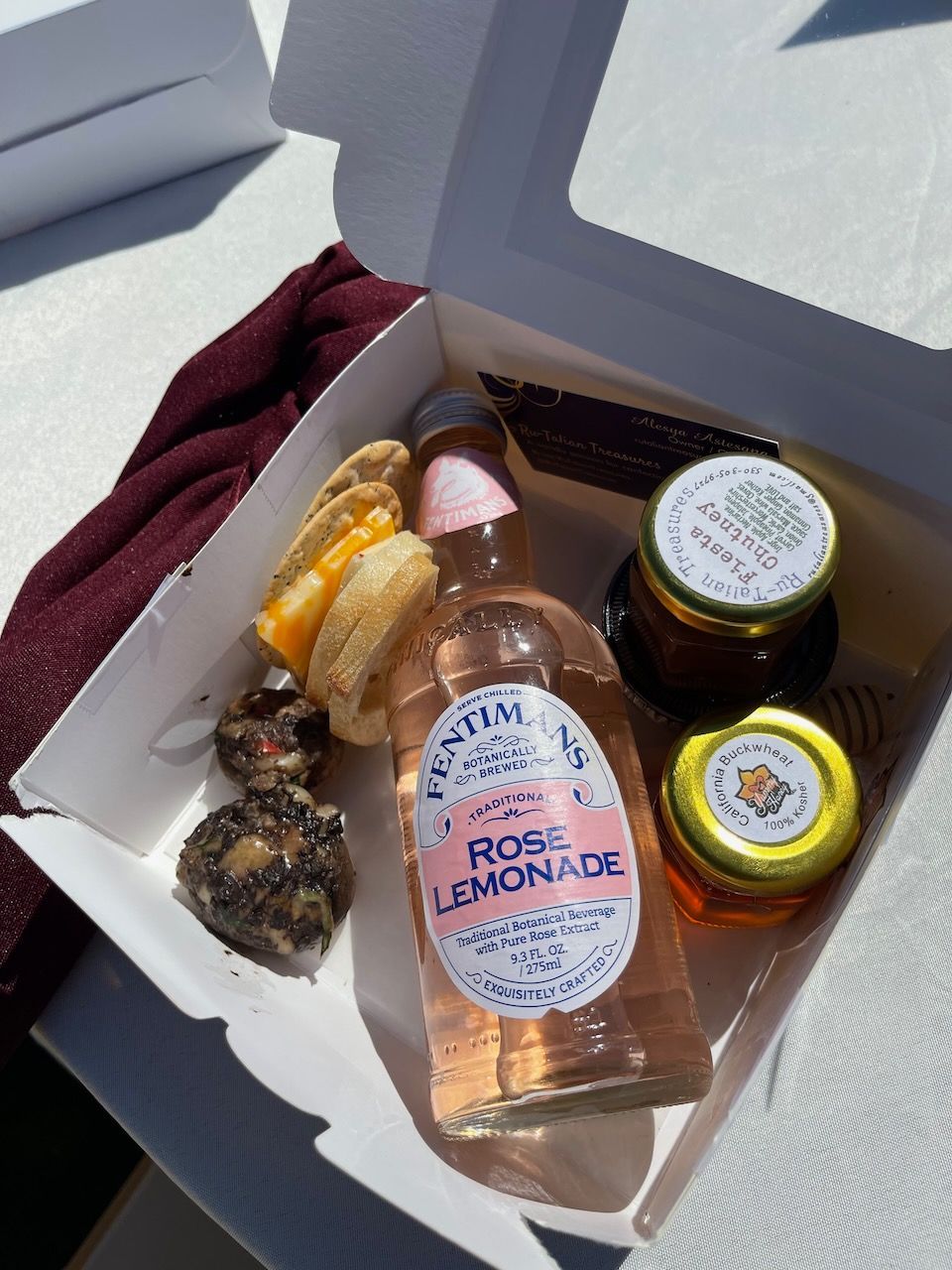 A box of food with a bottle of rose lemonade