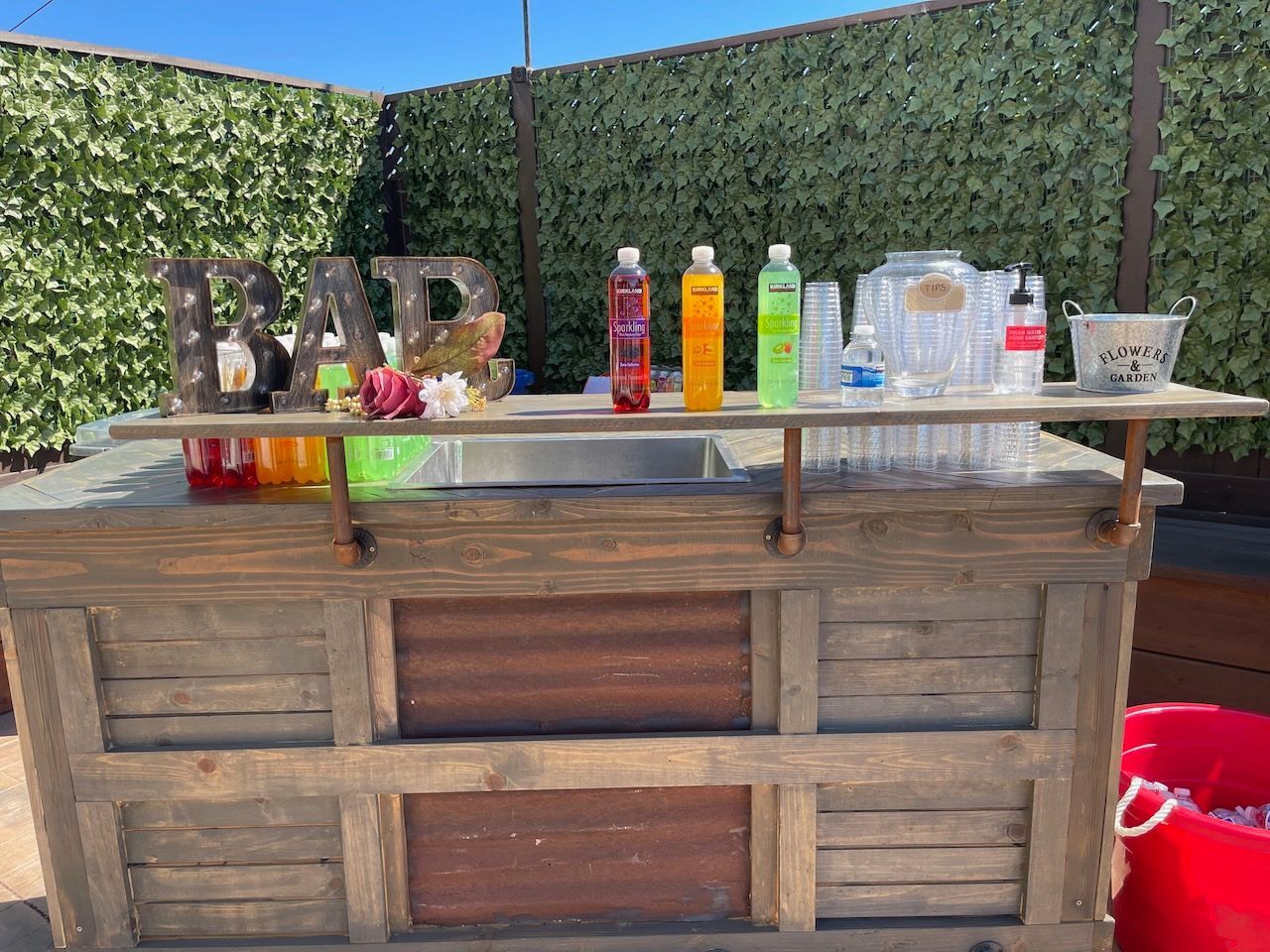 A wooden bar with bottles of drinks and glasses on it.