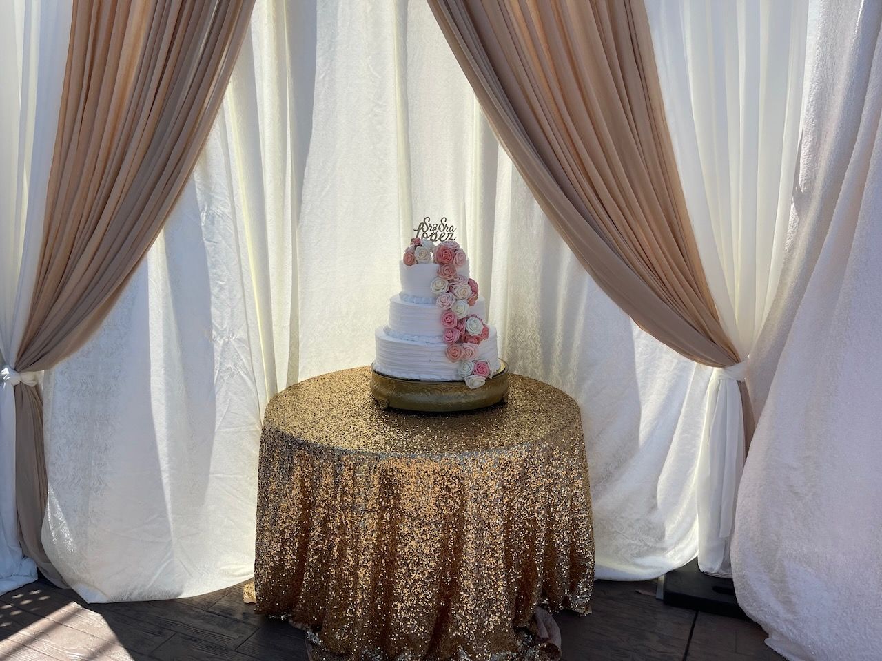 A wedding cake is sitting on a table under a canopy.