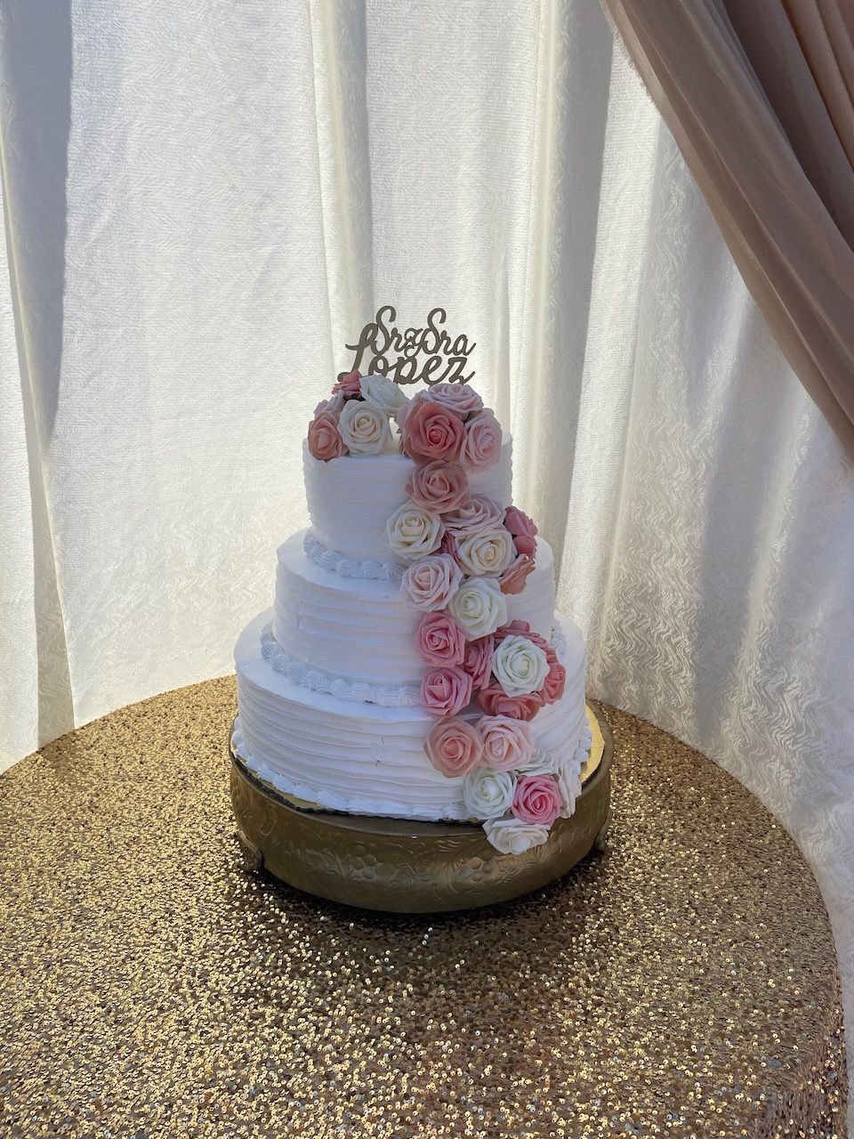 A wedding cake is sitting on top of a gold table.