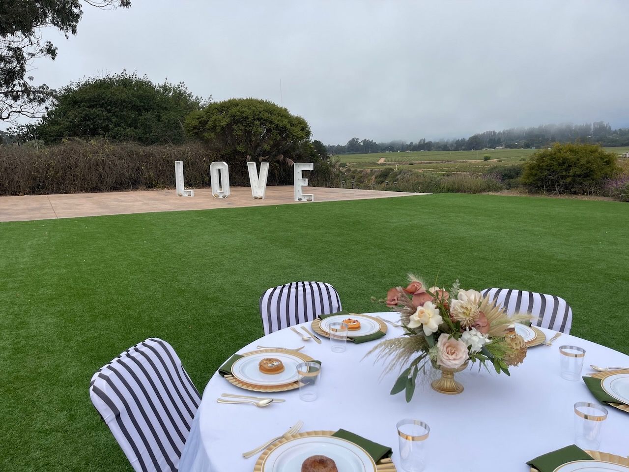 A table set for a wedding reception with a love sign in the background.